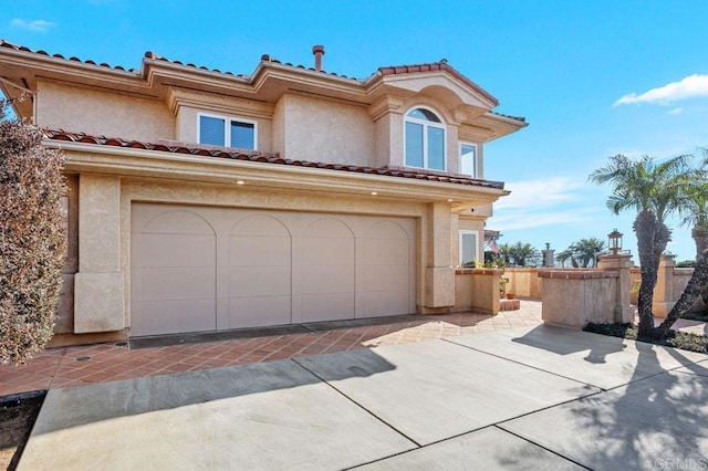 mediterranean / spanish home with a garage, fence, and stucco siding