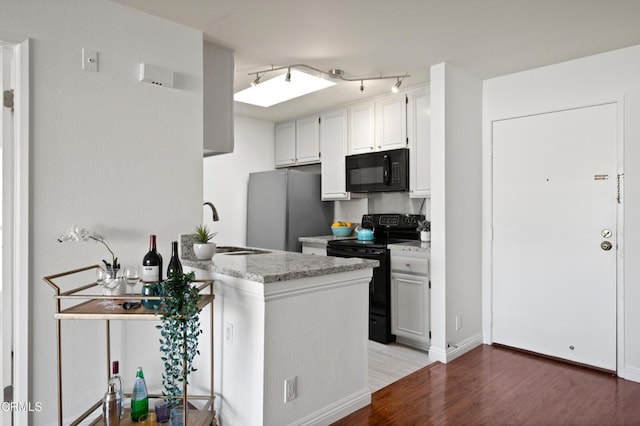 kitchen featuring hardwood / wood-style floors, black appliances, white cabinets, sink, and kitchen peninsula