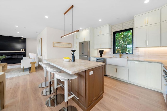 kitchen featuring sink, white cabinetry, a center island, pendant lighting, and stainless steel appliances