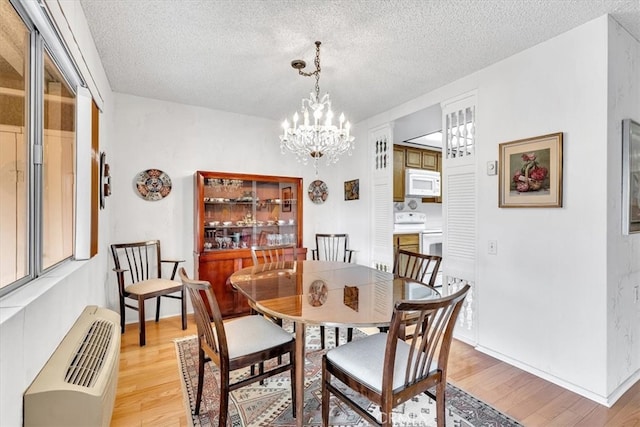 dining space featuring light hardwood / wood-style floors, a textured ceiling, and a chandelier