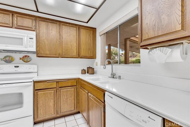 kitchen featuring light tile patterned floors, white appliances, and sink