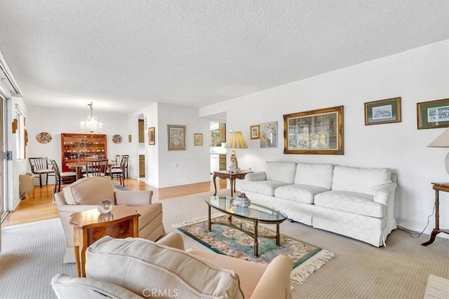 living room with light hardwood / wood-style flooring, a textured ceiling, and a notable chandelier