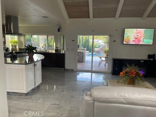 living room with wood ceiling, vaulted ceiling with beams, and sink