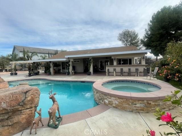 view of pool with an outdoor bar, a patio, and an in ground hot tub