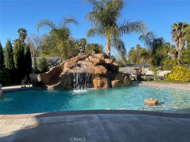 view of swimming pool with pool water feature and a water slide