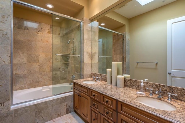 bathroom featuring a skylight, vanity, and enclosed tub / shower combo