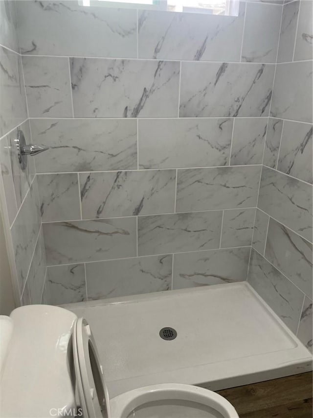 bathroom with tiled shower and toilet