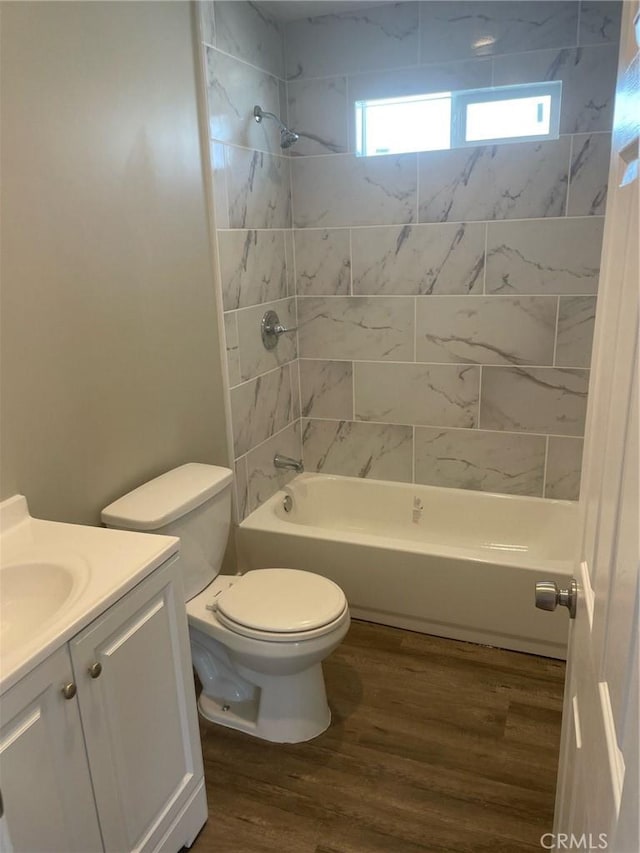 full bathroom with hardwood / wood-style floors, vanity, toilet, and tiled shower / bath