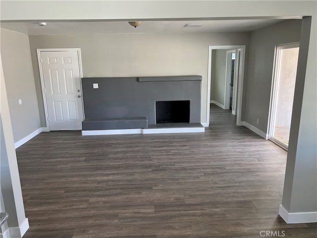 unfurnished living room featuring a wealth of natural light and dark wood-type flooring