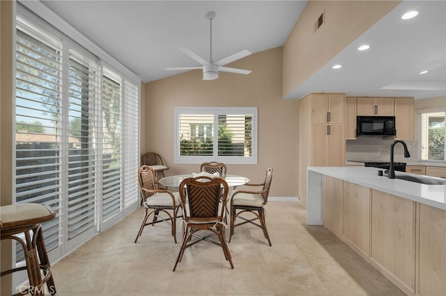 dining area featuring ceiling fan, a healthy amount of sunlight, sink, and vaulted ceiling