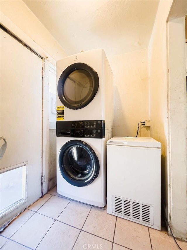 washroom with light tile patterned floors and stacked washer and dryer