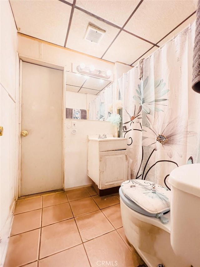 bathroom featuring a paneled ceiling, tile patterned flooring, and toilet