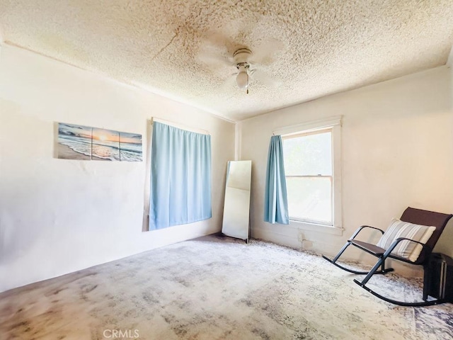 carpeted empty room with ceiling fan and a textured ceiling