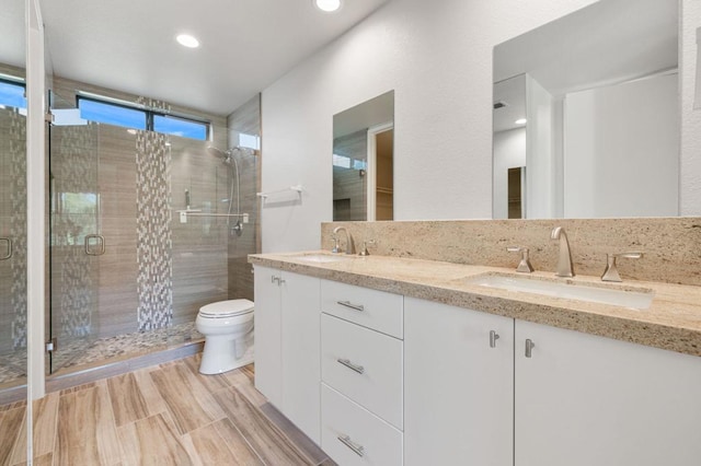 bathroom featuring wood-type flooring, vanity, toilet, and walk in shower