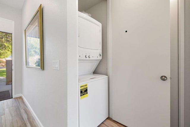 clothes washing area featuring stacked washing maching and dryer and light hardwood / wood-style floors