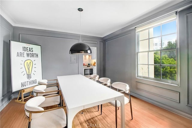 dining space featuring light hardwood / wood-style floors and crown molding