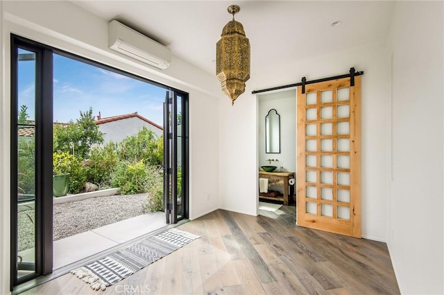 doorway with a wall mounted air conditioner, a barn door, and hardwood / wood-style flooring