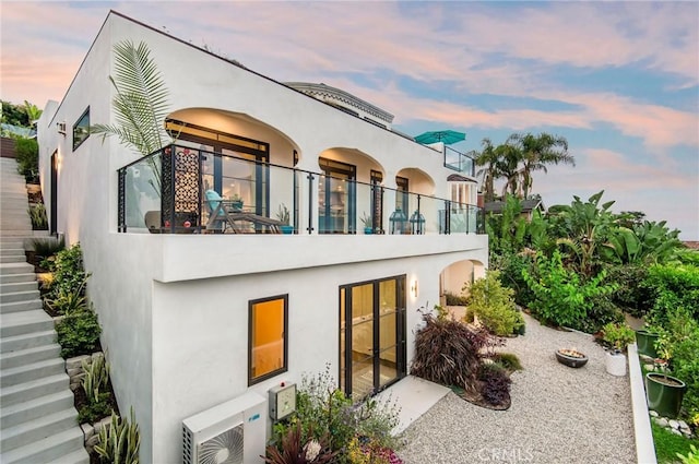 back of property featuring stucco siding, ac unit, and stairway