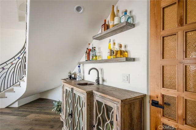 bar with stairs, dark wood-style floors, a sink, and wet bar