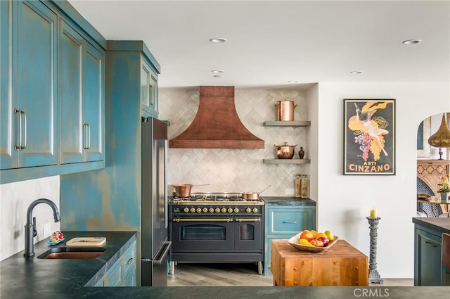 kitchen featuring stainless steel fridge, double oven range, tasteful backsplash, premium range hood, and a sink