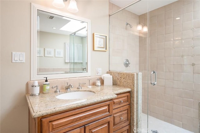 bathroom with vanity, a shower with shower door, and a skylight