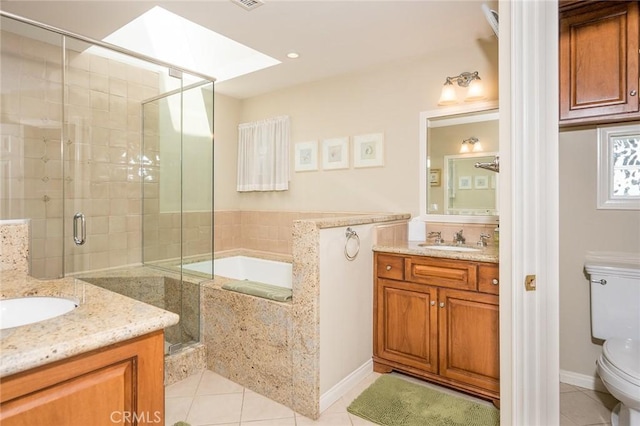 full bathroom with vanity, tile patterned floors, a skylight, toilet, and independent shower and bath