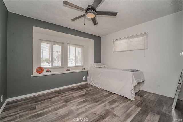 bedroom with ceiling fan, a textured ceiling, and dark hardwood / wood-style flooring