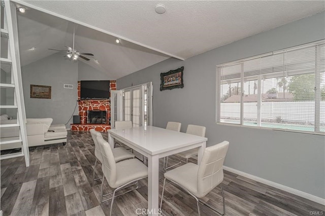 dining area featuring ceiling fan, lofted ceiling, a fireplace, and dark hardwood / wood-style floors