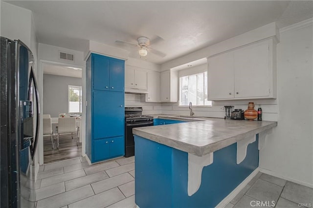 kitchen with white cabinets, black appliances, blue cabinetry, kitchen peninsula, and ceiling fan