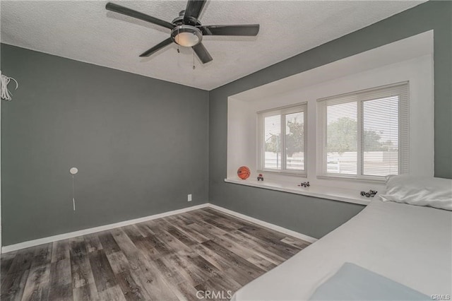 bedroom with dark wood-type flooring, ceiling fan, and a textured ceiling