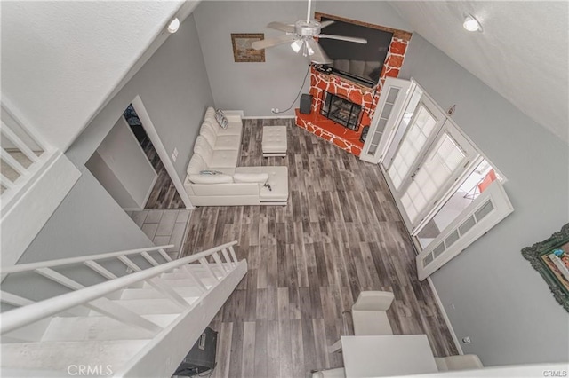 interior space featuring high vaulted ceiling, wood-type flooring, ceiling fan, and a fireplace