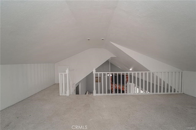 bonus room featuring light carpet, vaulted ceiling, and a textured ceiling