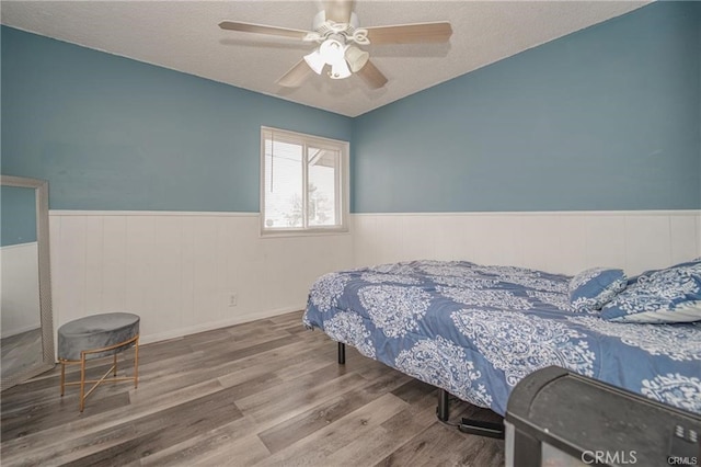 bedroom with a textured ceiling, ceiling fan, and hardwood / wood-style flooring