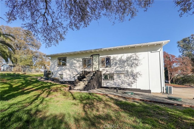 rear view of property featuring a lawn and central AC unit