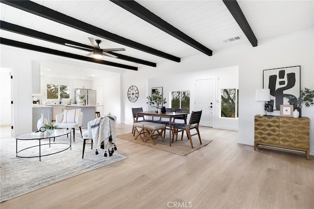 dining space featuring beam ceiling, ceiling fan, and light wood-type flooring