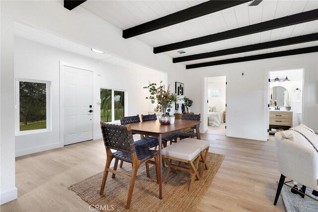 dining room with light hardwood / wood-style floors and beam ceiling