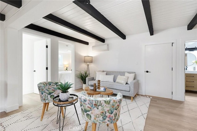 living room featuring beam ceiling, an AC wall unit, and light hardwood / wood-style flooring