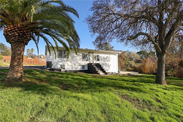 rear view of property featuring central AC and a yard