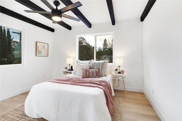 bedroom featuring ceiling fan, light hardwood / wood-style flooring, and beamed ceiling