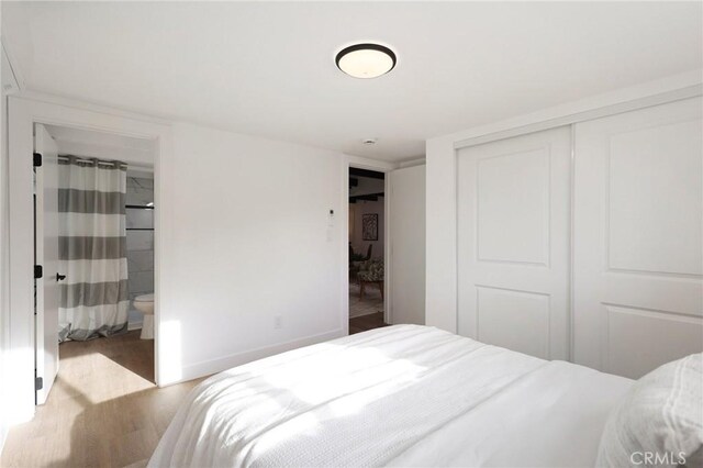 bedroom with ensuite bathroom, a closet, and light hardwood / wood-style flooring