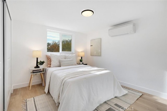 bedroom with electric panel, light hardwood / wood-style flooring, and a wall unit AC