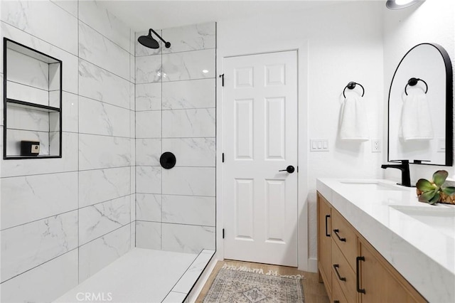 bathroom featuring hardwood / wood-style flooring, vanity, and a tile shower