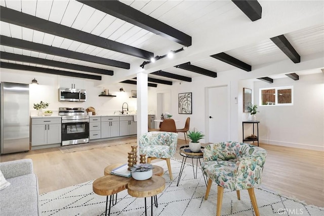 living room featuring sink, beamed ceiling, and light wood-type flooring