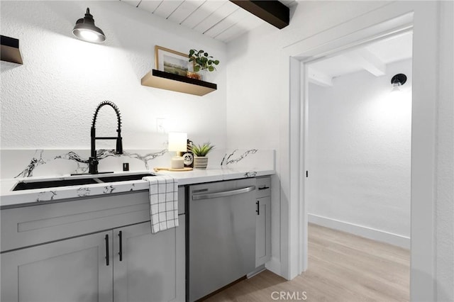 kitchen with gray cabinetry, sink, beamed ceiling, stainless steel dishwasher, and light wood-type flooring