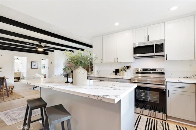 kitchen with white cabinets, appliances with stainless steel finishes, light hardwood / wood-style floors, and beam ceiling