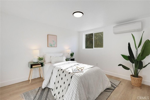 bedroom featuring a wall unit AC and light wood-type flooring