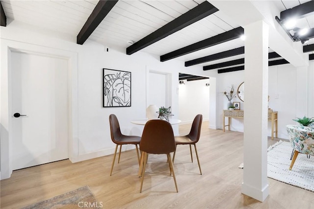 dining space featuring light hardwood / wood-style flooring and beamed ceiling