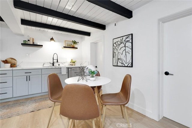 dining room featuring sink, beamed ceiling, and light hardwood / wood-style flooring