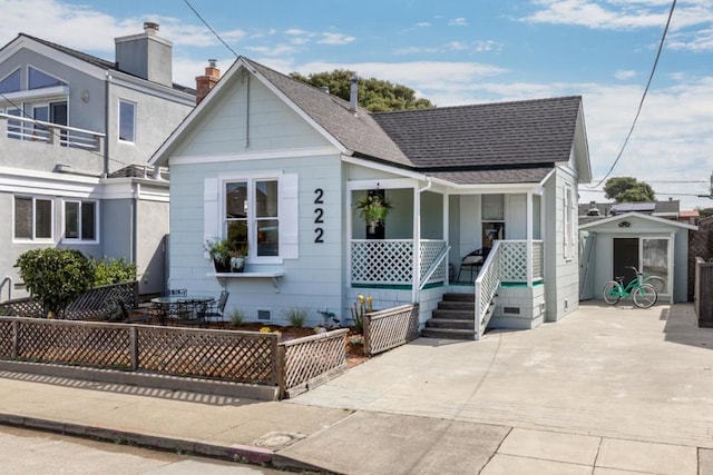 bungalow-style home featuring covered porch and a shed