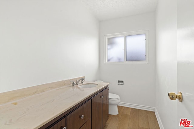 bathroom featuring vanity, toilet, wood-type flooring, and a textured ceiling